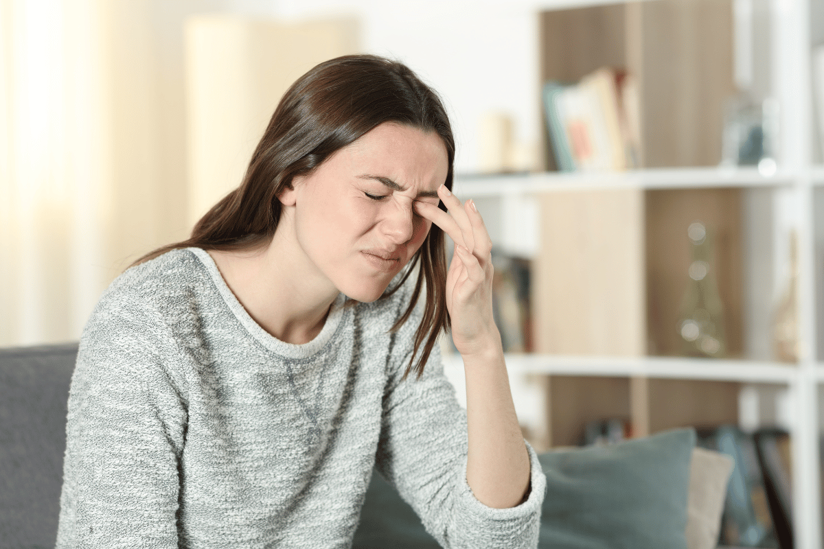 young woman looking uncomfortable and touching her eye